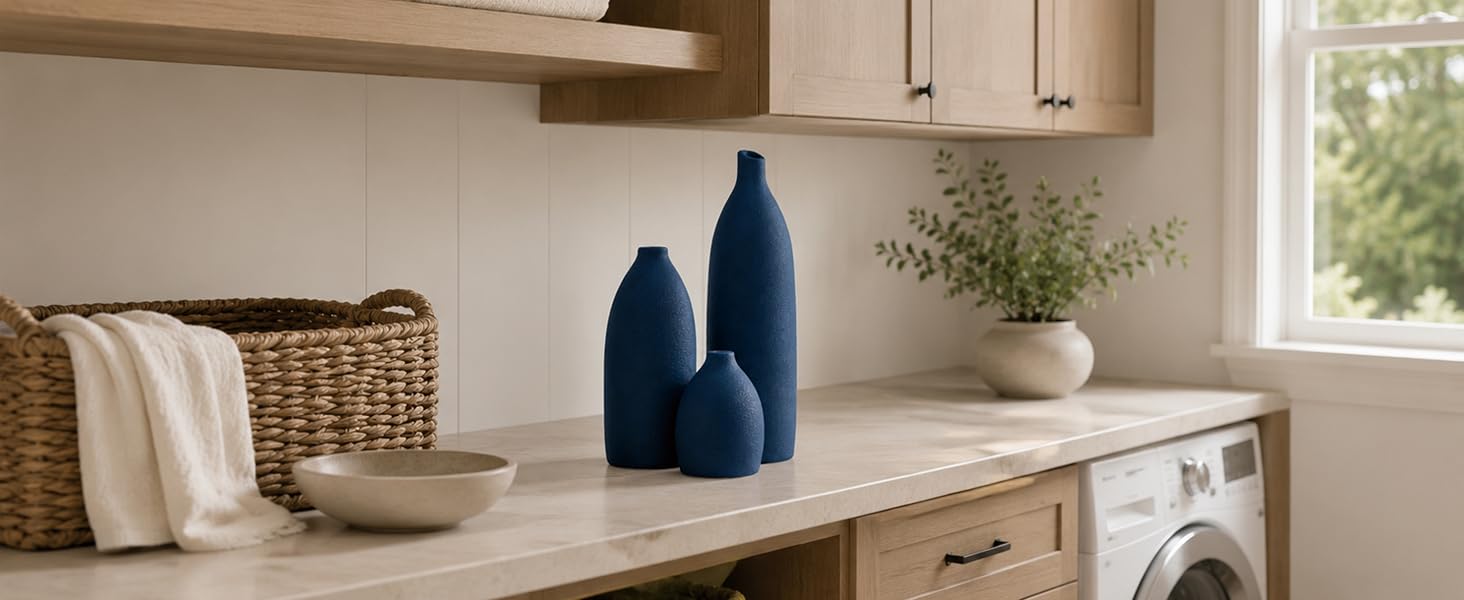 Coastal blue ceramic vase set on a laundry room countertop with natural wood cabinets.