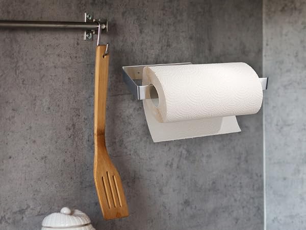 Wall-mounted paper towel holder with floral wallpaper accent visible in background. Multiple views show chrome fixture against gray concrete wall.