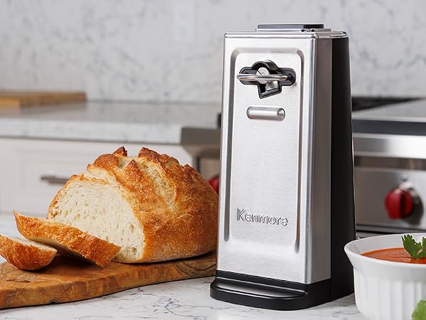 Kenmore smooth-edge can opener on a white marble countertop with a loaf of bread and bowl of soup
