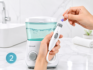 Hands holding white and blue oral irrigation device with water reservoir, demonstrating dental cleaning tool usage.