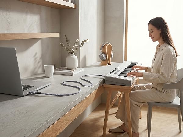 Girl playing a white MIDI keyboard connected to a laptop with a Ruaeoda USB A to B MIDI cable.