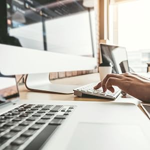 Hands shown working on Apple computer and devices