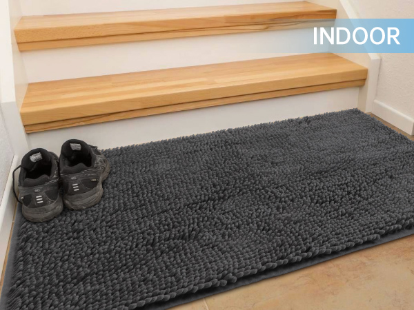 A chenille doormat placed beside the indoor staircase, and a pair of shoes is also put on it.