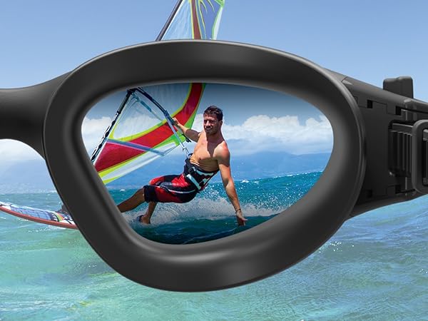 Black-framed sunglasses lens reflecting a windsurfer in action on blue water, demonstrating the clarity and field of view of the eyewear.