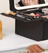 Black cosmetic case displaying various makeup brushes and tools arranged inside, seen from above on a white surface.