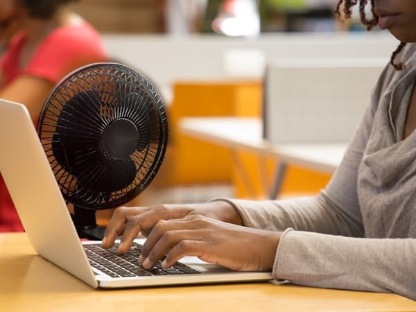 Compact clip-on fan securely attached to desk, providing quiet and efficient personal cooling