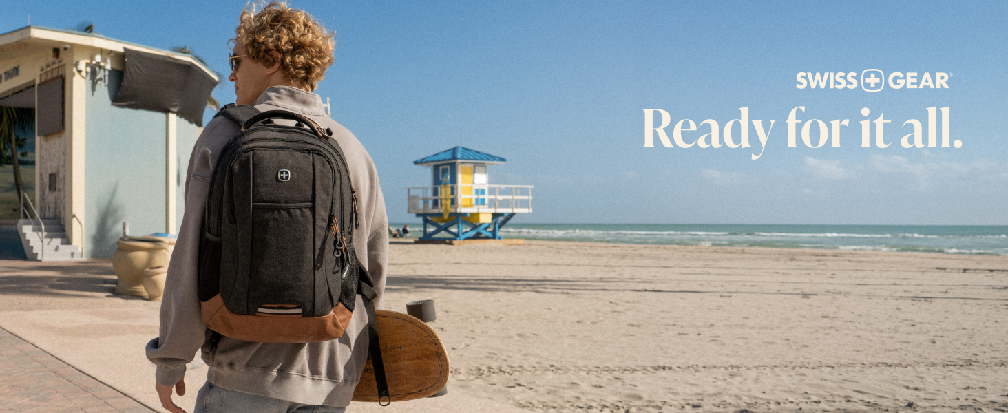 Person walking on a beach wearing a charcoal laptop backpack with a tan leather base