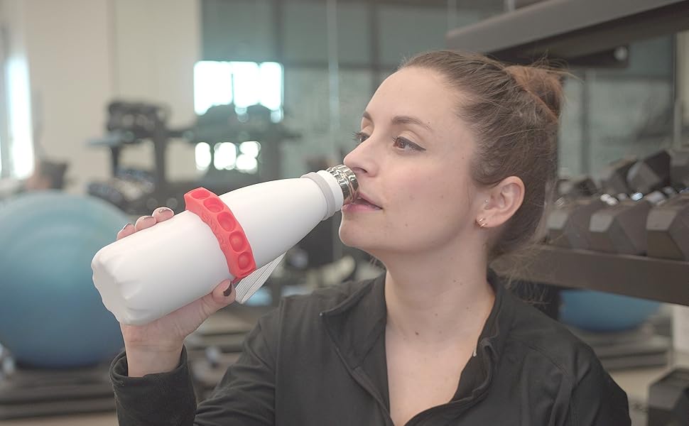 Woman sitting in gym drinking from bottle with GWaT tracker attached.