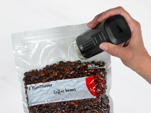 Hand holding a vacuum device over sealed coffee beans