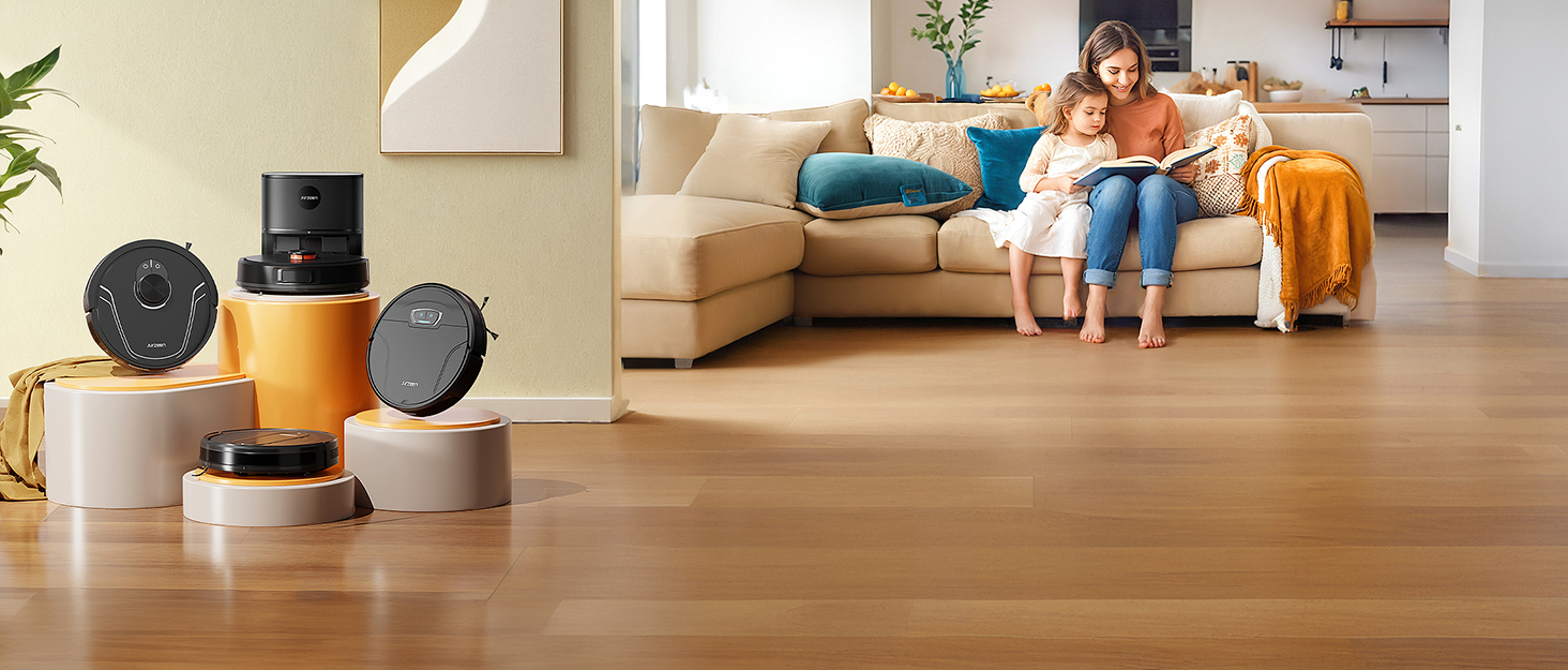 Multiple robotic vacuum cleaners displayed on hardwood flooring in a living room setting. Various models shown in black and metallic finishes with round disc-shaped designs.