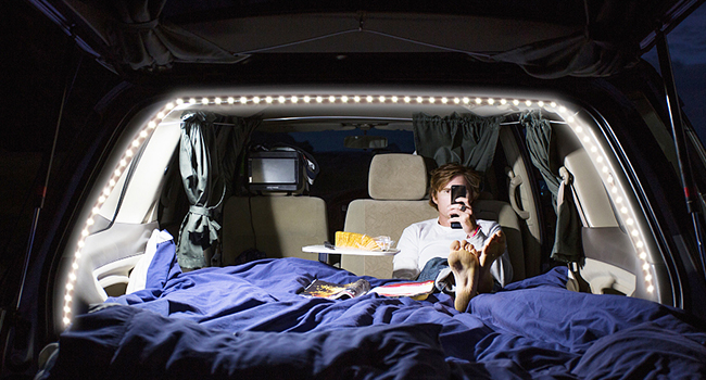 a man sitting in a car with a cell phone in his hand.