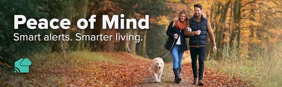 Couple walking their dog on a wooded path in the fall: Peace of Mind Smart alerts. Smarter Living.
