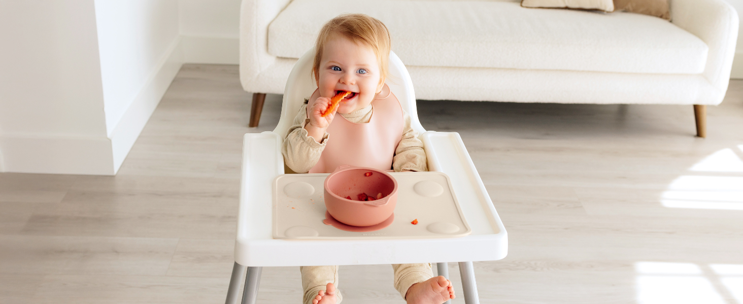 Baby enjoying food in high chair with Prep silicone placemat during happy feeding moments.