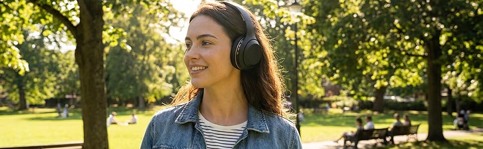 woman wearing a Sentry anc headphone outside in a park on a sunny day