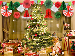Decorated Christmas tree with lights and ornaments, surrounded by presents and paper fan decorations in red, white, and green hanging above.