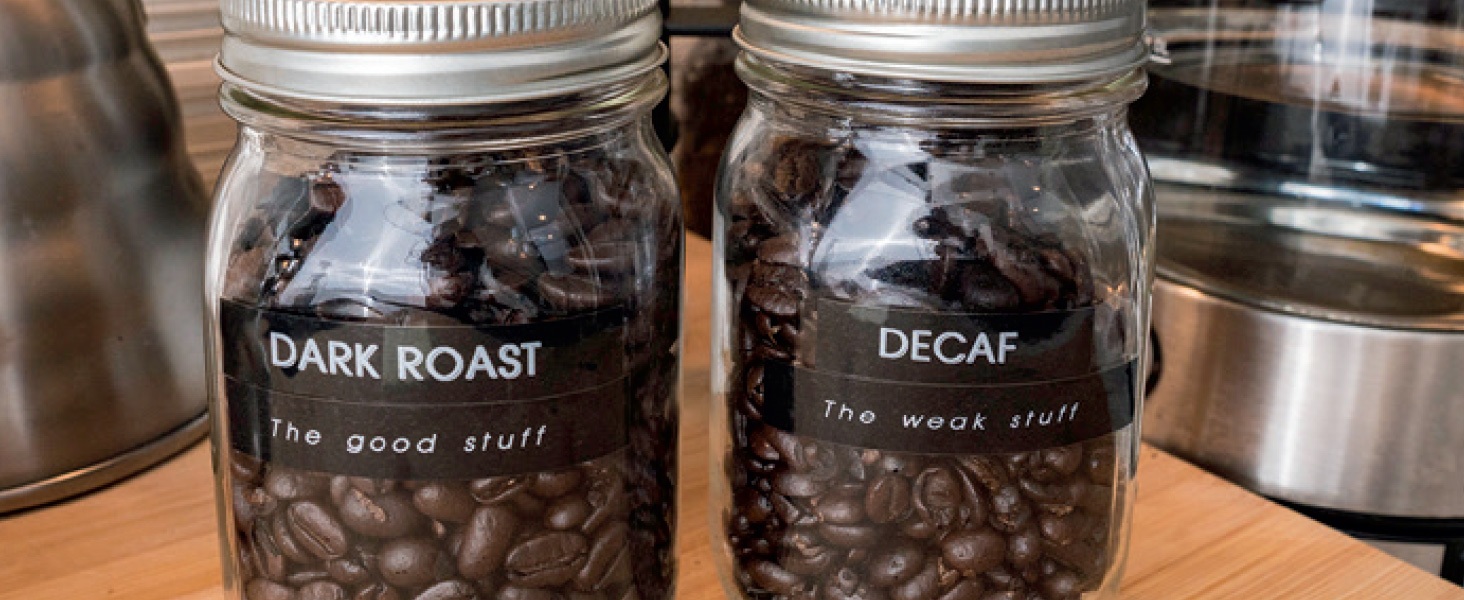 Mason jars filled with whole coffee beans, labeled "Dark Roast" and "Decaf"