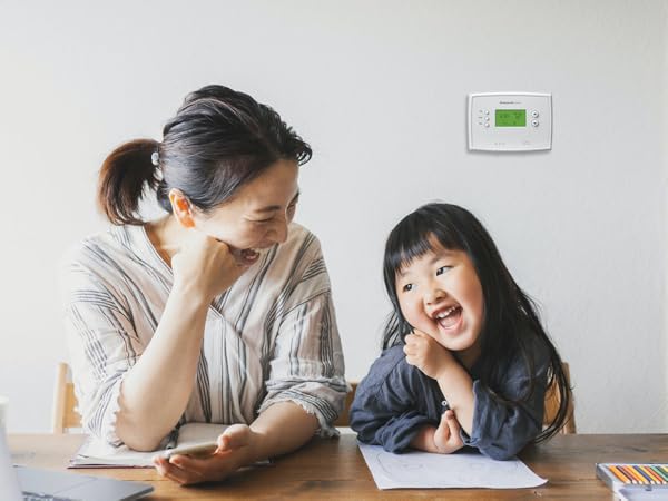 Mom and daughter sitting in front of the 5-2 Day Programmable Thermostat