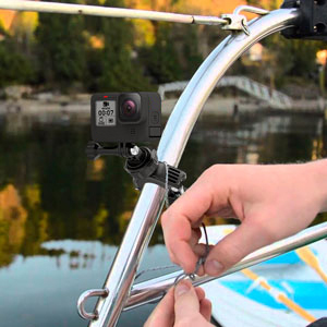 Hand adjusting water flow control on blue kayak or water sports equipment near water with blurred green background.