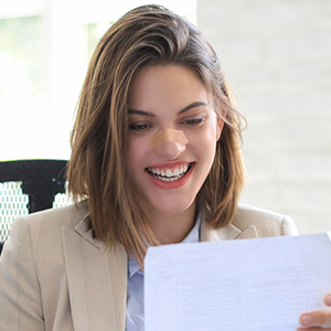 Professional office setting with document being reviewed, featuring beige blazer and natural lighting.