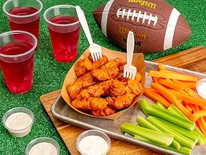 Forks sticking out of chicken wings. Drinks and sauces to the side.