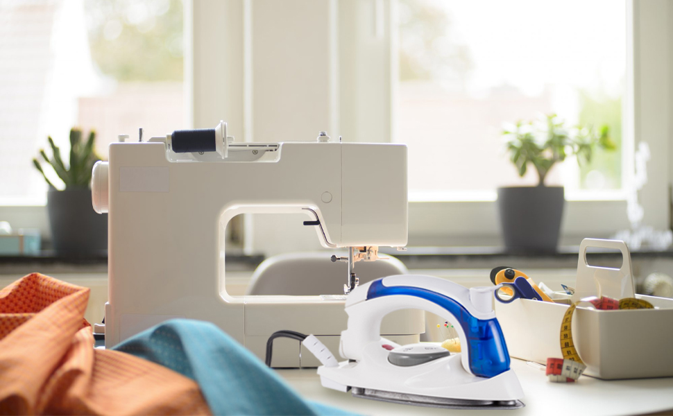 Travle iron is next to a sewing machine and is a necessity for sewing.