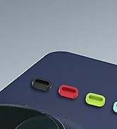 Navy blue surface with four small oval-shaped accessories in black, red, lime green, and light blue colors. Partial view of a circular object in foreground.