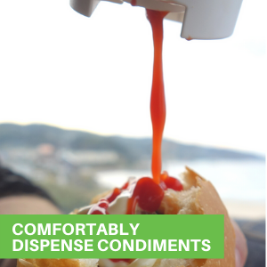 A person using a ketchup squeeze bottle to dispense tomato sauce on a burrito.