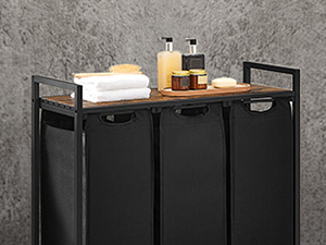 Black metal laundry sorter with wooden top shelf. Three fabric compartments for sorting. Bathroom essentials displayed on top.