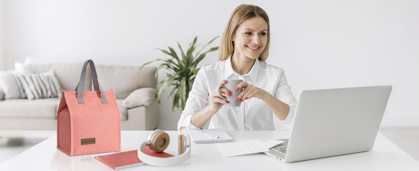 Workspace scene with laptop, coral-colored tote bag, and indoor plants in bright, modern setting.