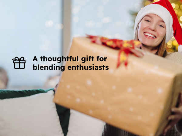 Smiling woman opens a holiday gift, presenting the blender as a gift for blending enthusiasts.