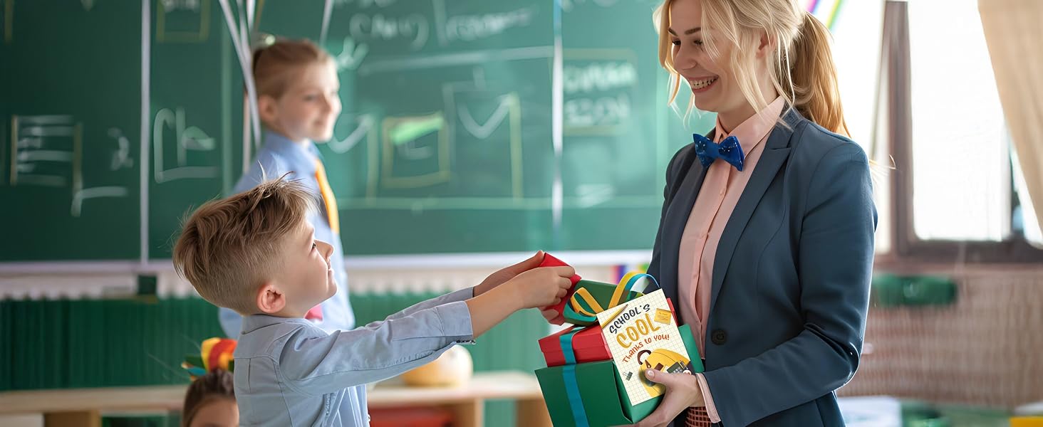A student hands a gift and teacher greeting card to a smiling teacher in a decorated classroom.