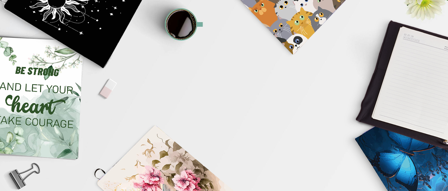 Flat lay of office supplies including notebooks, pens, and decorative items on a white surface. Partial view of a motivational card visible.