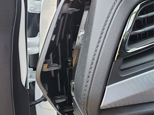 Close-up of a car door hinge and frame, showing the connection between the door and the vehicle body. Visible are metal components and rubber seals.