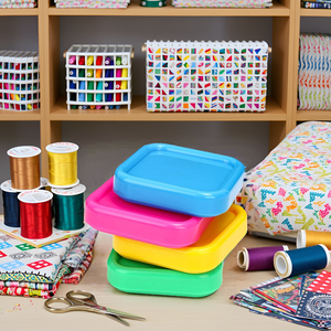 A sewing table with various colorful fabrics, threads, and the product neatly arranged.