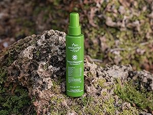 A green bottle of Absolutely Natural Insect Repellent is placed on a rugged outdoor setting.