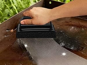 Hand using black cleaning or polishing tool on reflective surface, creating visible shine marks on the material.