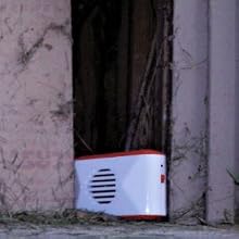 Ultrasonic pest repeller set up in the corner of a wooden shed
