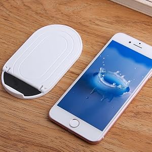 Oval-shaped white wireless charging pad next to a smartphone on wooden surface. The phone displays a water splash image on its screen.