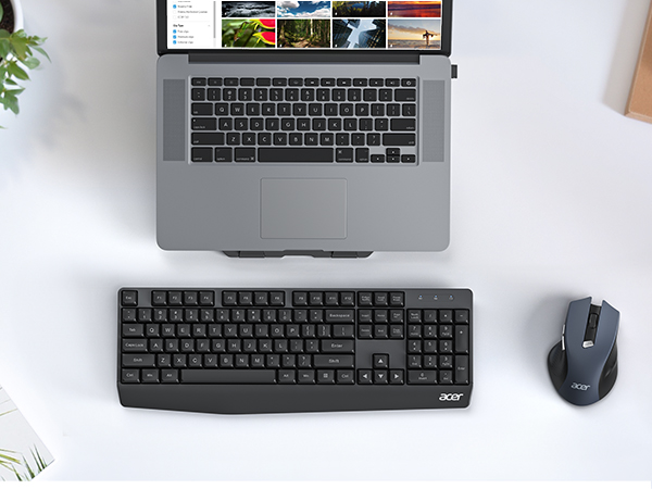 Laptop on desk with external keyboard and mouse. Keyboard is full-size with number pad. Mouse is wireless. Laptop screen displays multiple images.