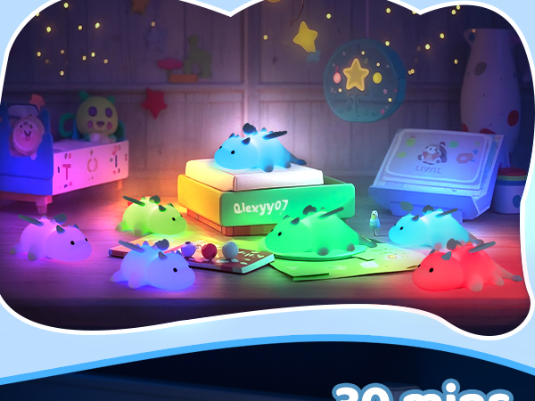 Colorful, glowing animal-shaped night lights in various hues scattered around a dimly lit child's room. Central light on a box emits green illumination.