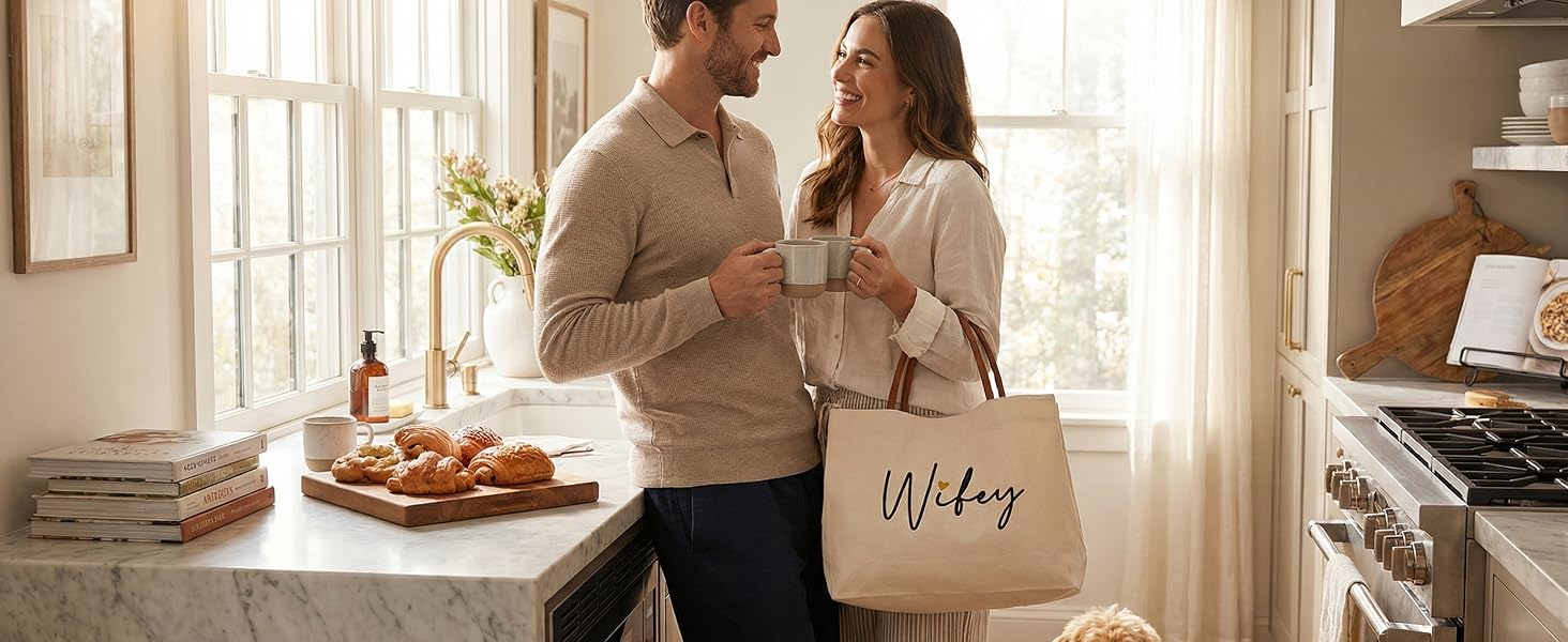 A couple in a kitchen with the woman carrying a Wifey canvas tote bag during a coffee morning.