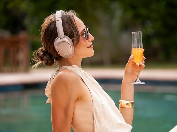 A woman wearing lux headphones by the pool while relaxing
