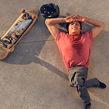 A man lying next of his skateboard