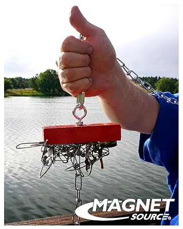 Image of hand holding fishing magnet with metal scraps attached to base.