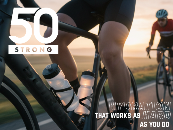 Cyclist riding at sunrise with 50 Strong 22 oz bottle in black cage on bike frame.