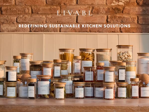 Collection of glass jars filled with various dry goods on wooden shelf. Text above reads 'PIVARI: REDEFINING SUSTAINABLE KITCHEN SOLUTIONS'. Exposed brick wall visible in background.