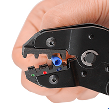 Close-up of a hand holding a black wire crimping tool with blue and red components visible in the crimping area.