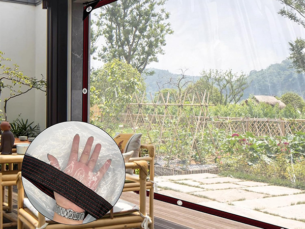 Transparent mesh screen with hand pressing against it, demonstrating its flexibility. Outdoor patio view with wooden chairs visible in background.