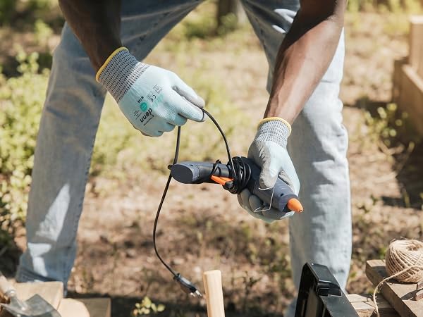 Worker handling a power tool outdoors wearing Safedenn cooling work gloves for heat relief.