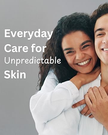 Text reads 'Everyday Care for Unpredictable Skin'. Portrait of smiling couple embracing, woman with dark curly hair wearing white long-sleeve top, man in light colored shirt on gray background.